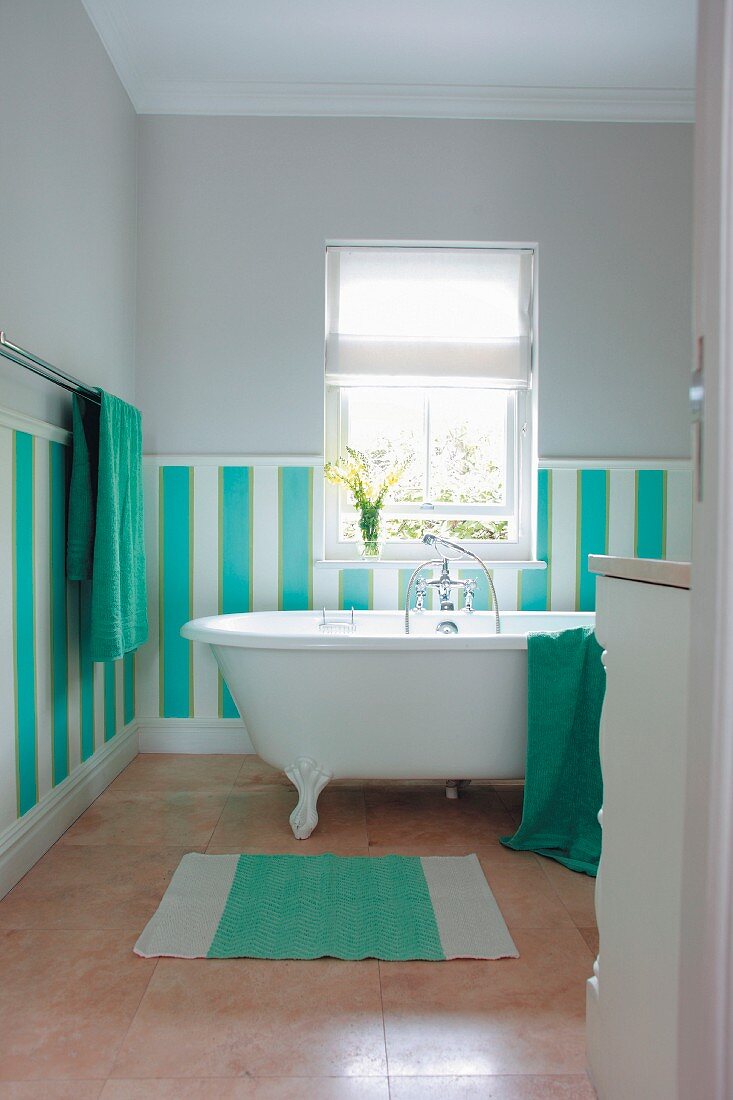 Dado in wide stripes of turquoise and white on bathroom wall behind free-standing bathtub