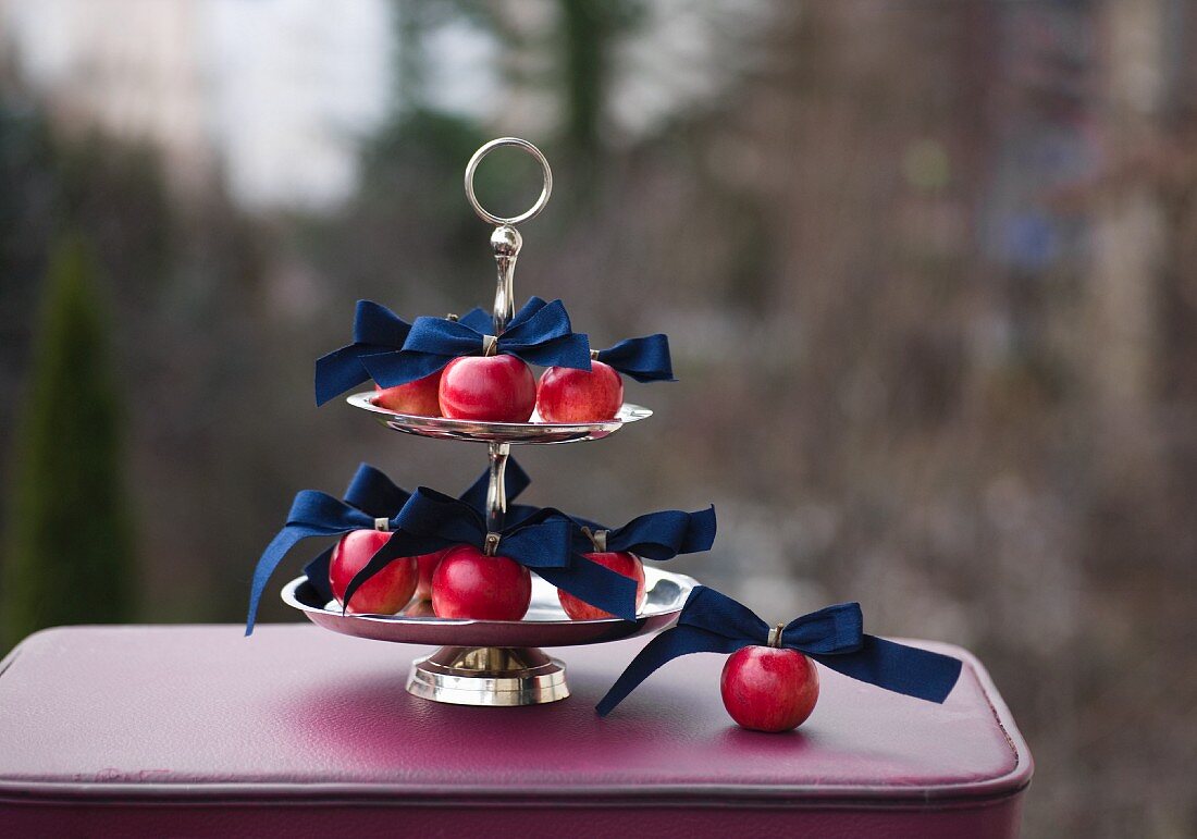 Red apples and dark blue ribbons on silver cake stand