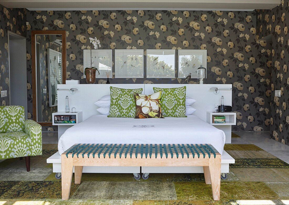 Schlafzimmer mit Retroflair, dunkelgrauer Blumentapete und moderner Holzkleiderbank