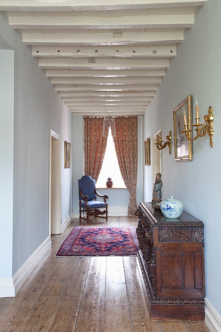 White-painted, restored wood-beamed ceiling in narrow hallway of period apartment furnished with period furniture