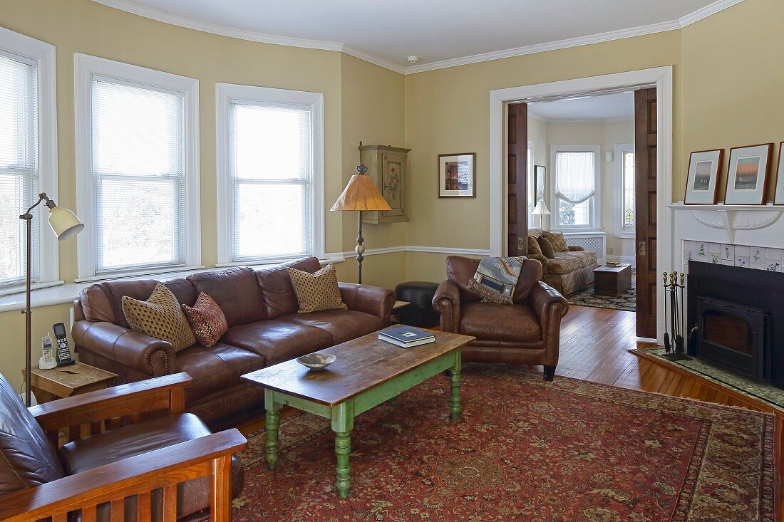 Coffee table with green-painted frame, brown leather sofa and matching armchair in living room