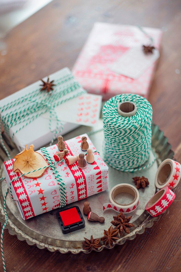 Weihnachtlich verpacktes Geschenk und Verpackungsutensilien in einer Tarteform