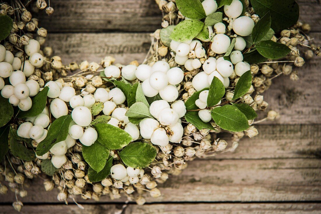 Wreath of snowberries on rustic wooden surface