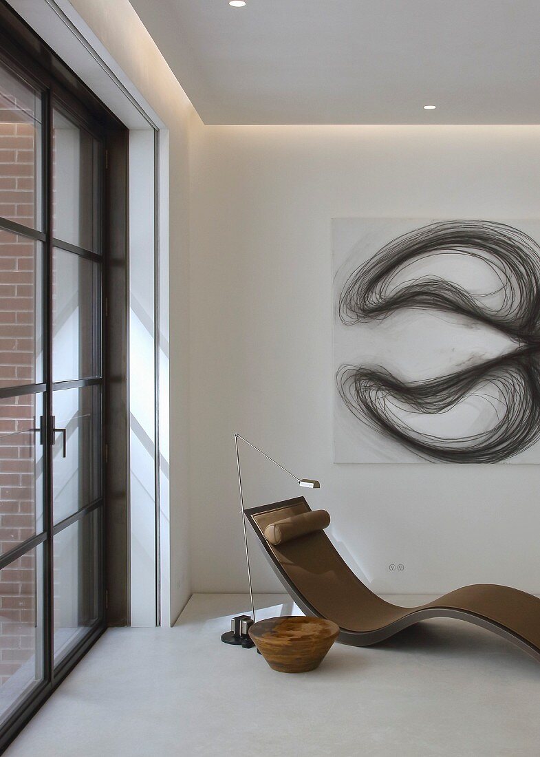 Designer chaise below modern artwork on wall in corner
