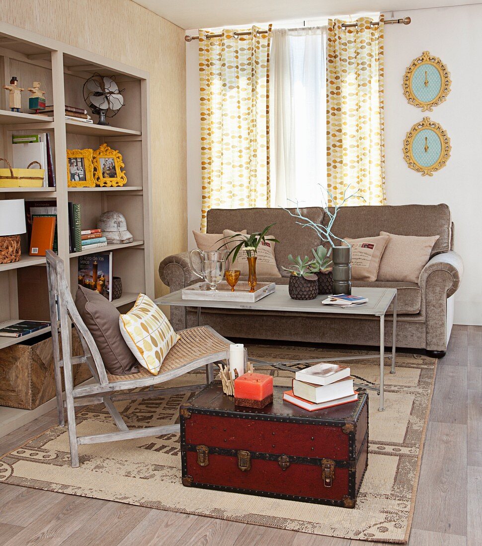 Wohnzimmer im beigefarbenem Look mit nostalgischem Reisekoffer, Teppich und offenem Regal