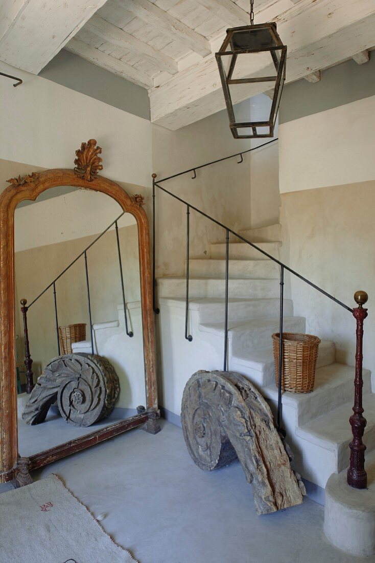 Masonry winding staircase, old full-length mirror and vintage, spiral, architectural wooden element in rustic stairwell