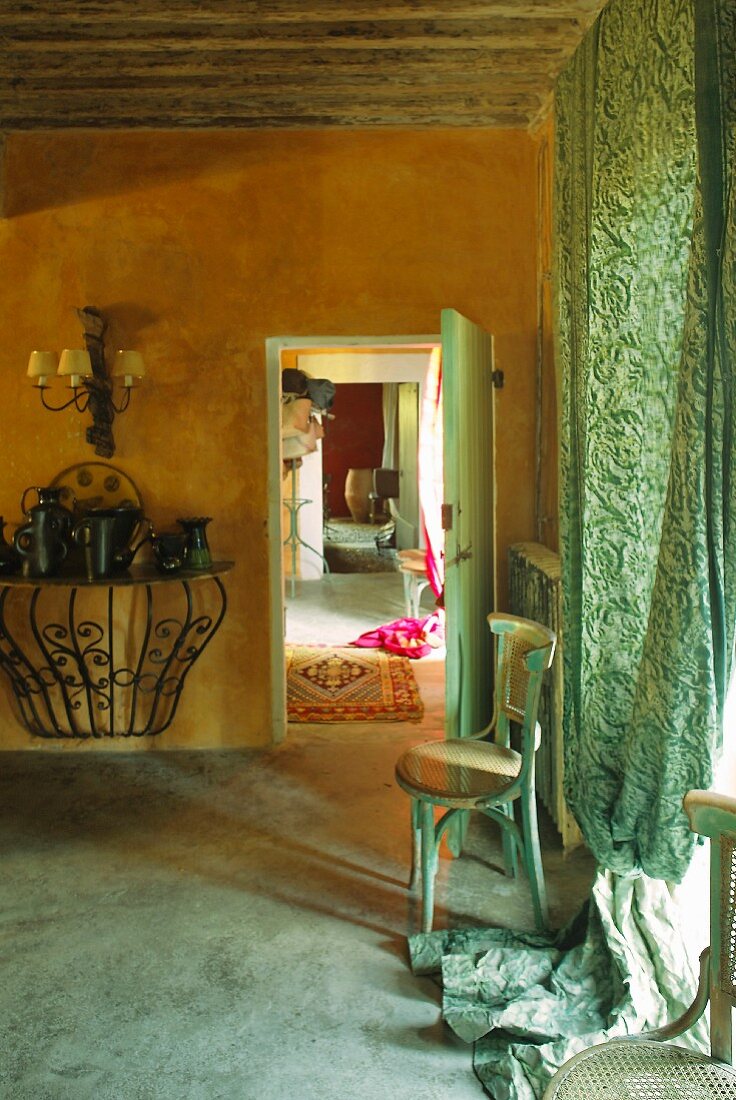 Ochre interior with green. floor-length curtains on window and wooden chair