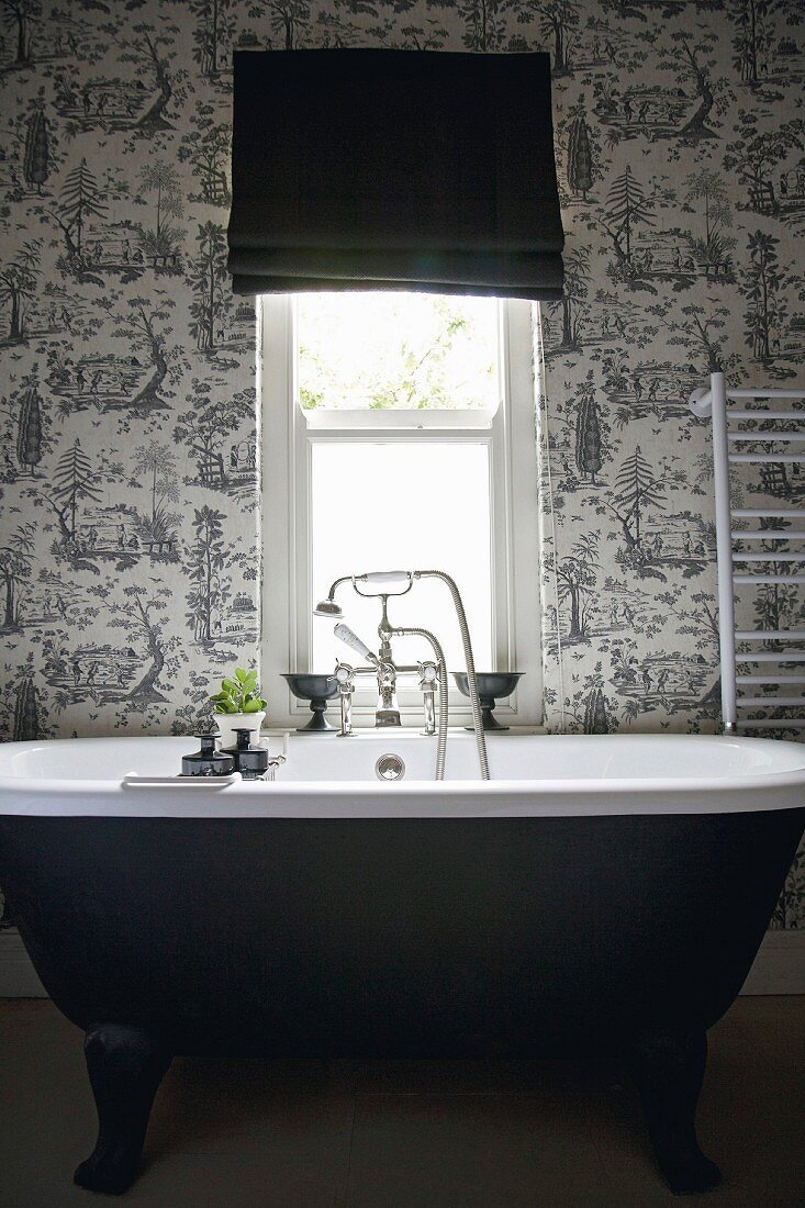Schwarze, freistehende Badewanne vor schwarz-weißer Toile-de-jouy Tapete
