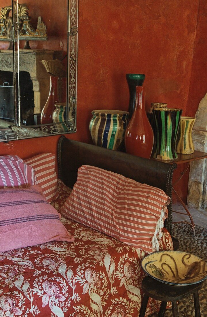 Floral blanket and striped cushions on sofa next to collection of vases on side table