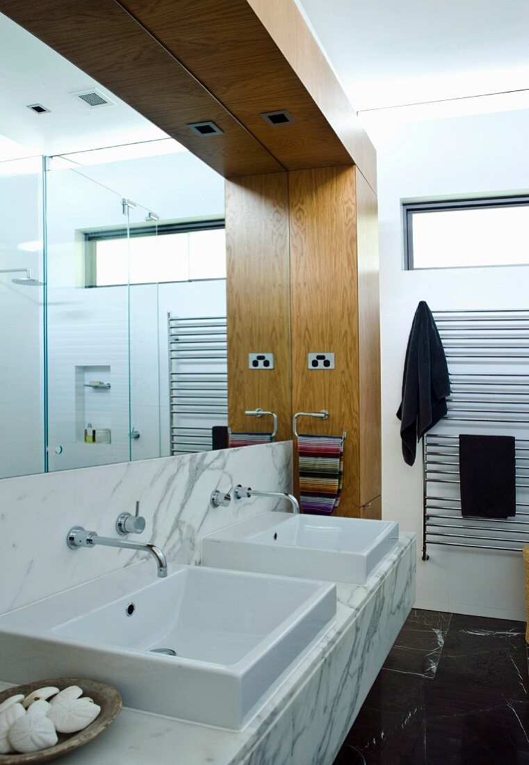 Washstand with twin sinks against mirrored wall in modern bathroom