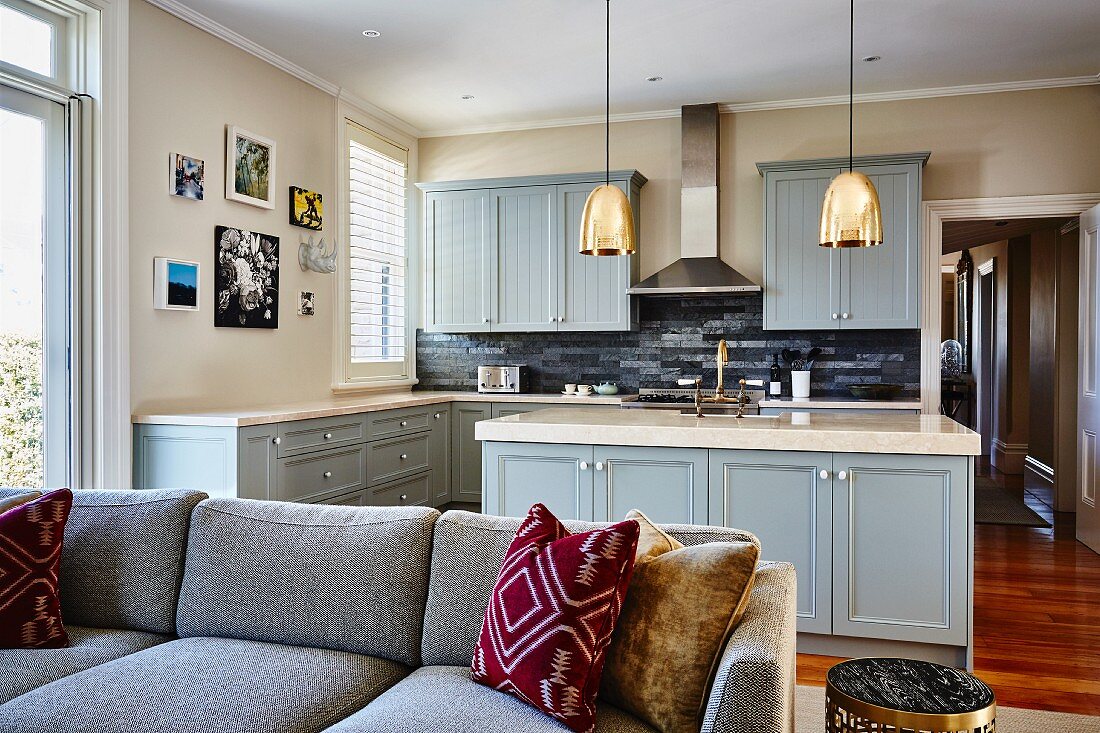View past sofa into open-plan country-house-style kitchen with grey-blue fronts