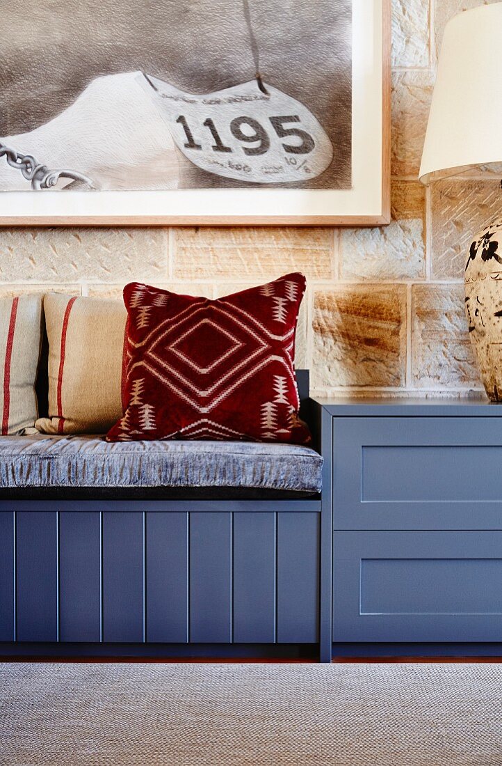 Patterned cushions on blue bench against stone wall