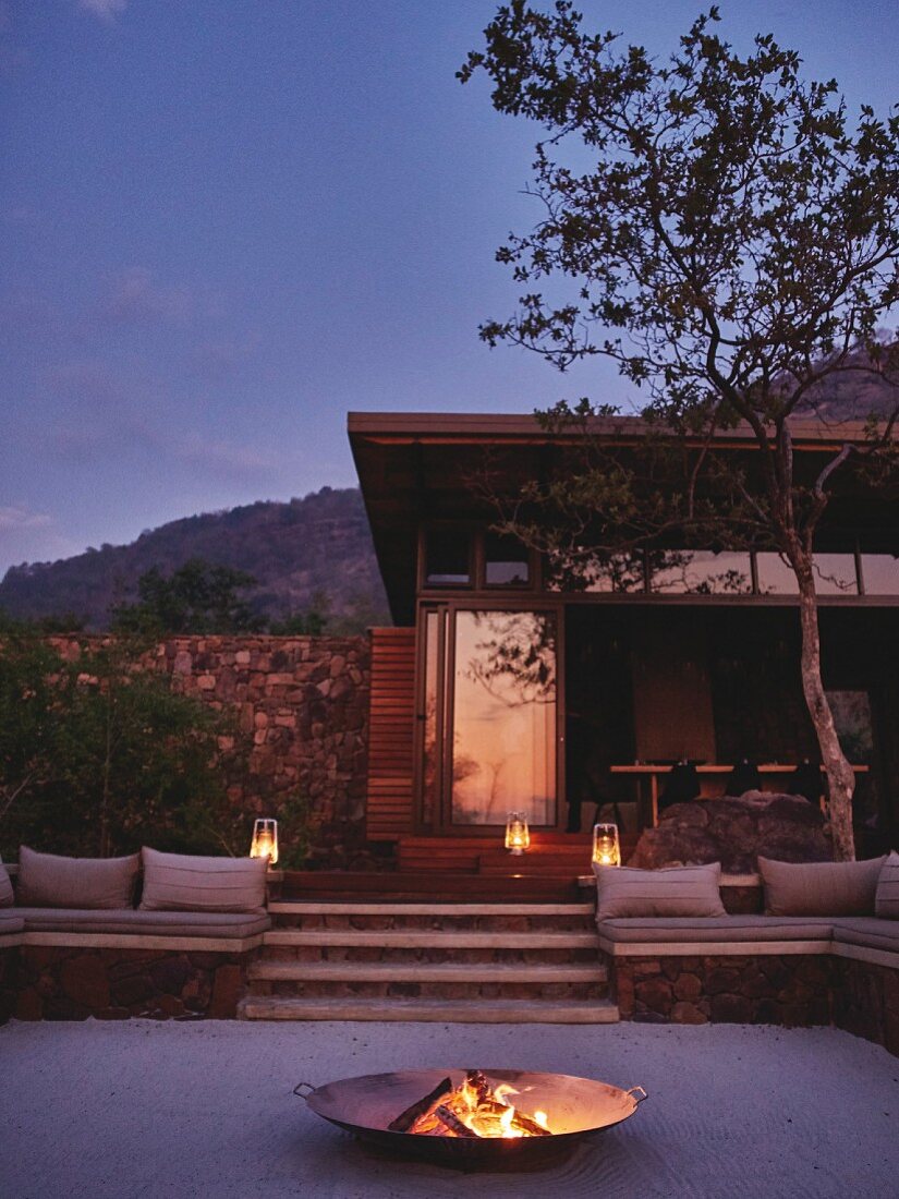 Twilight atmosphere in outdoor seating area with fire in fire bowl on terrace