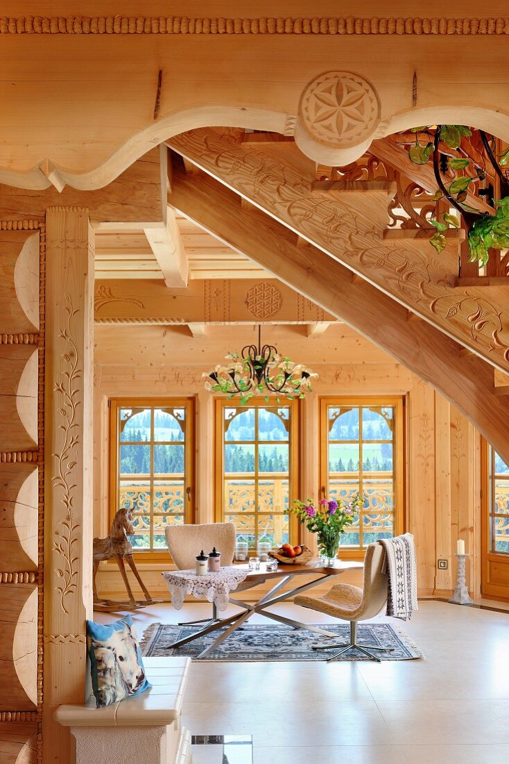 Blick unter Treppenlauf auf moderne Stühle um Tisch im Wohnbereich im Massivholzhaus
