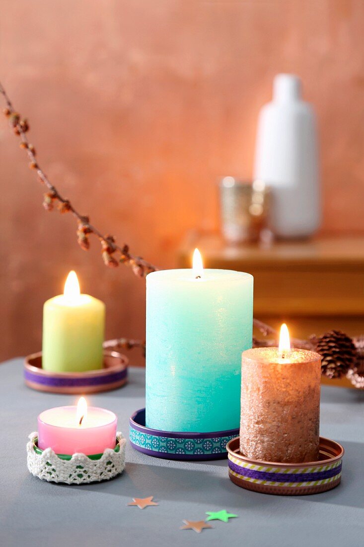 Bunte Kerzen in gebastelten Untersetzern aus Deckeln