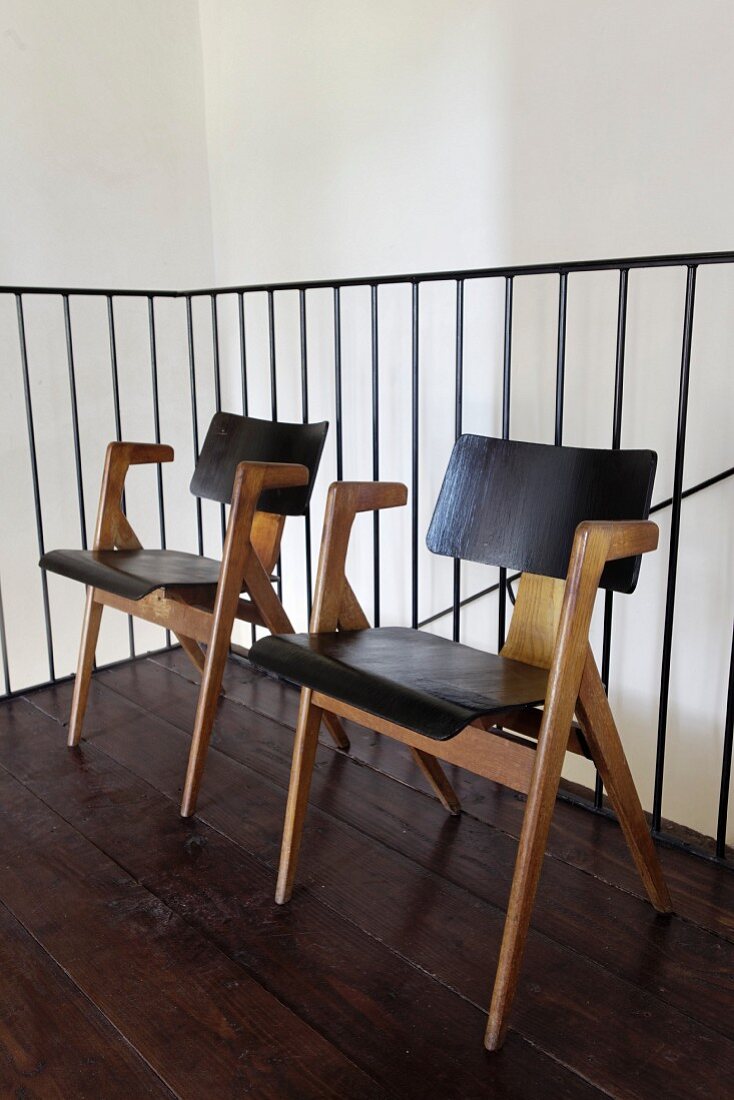Retro Stühle aus hellem Holzgestell vor Metall-Treppengeländer