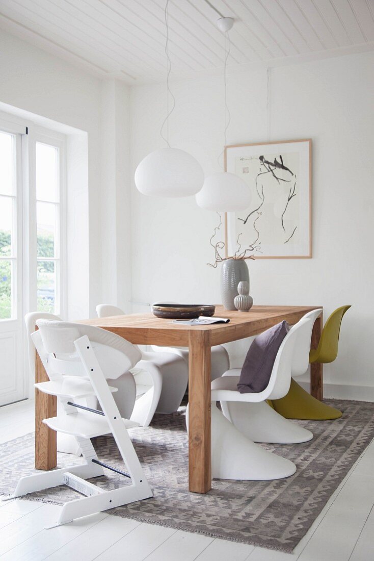 Weißes Esszimmer mit Holztisch und Designerstühlen