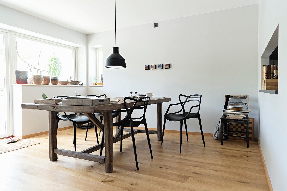 Rustikaler Holztisch und Designerstühle in minimalistischem Esszimmer