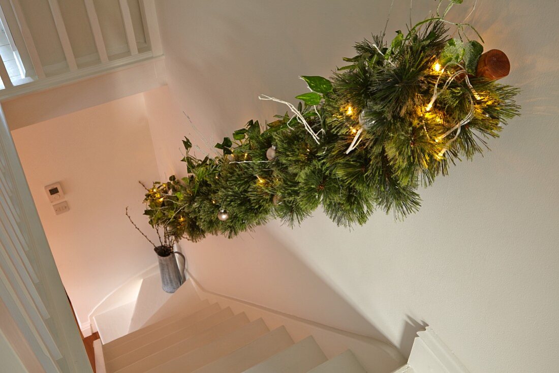 Weihnachtlich geschmückter Handlauf in ländlichem Treppenhaus mit Blick auf Treppenlauf