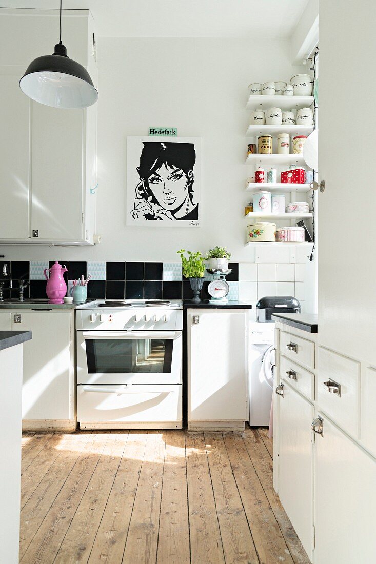 weiße Küche mit rustikalem Dielenboden und schwarz-weißem Pop Art-Poster