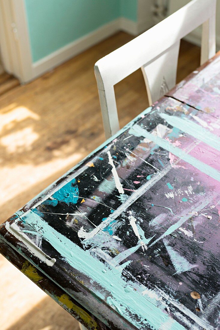 Tischplatte mit verschiedenen Farbrändern und Farbklecksen neben weißer Stuhllehne
