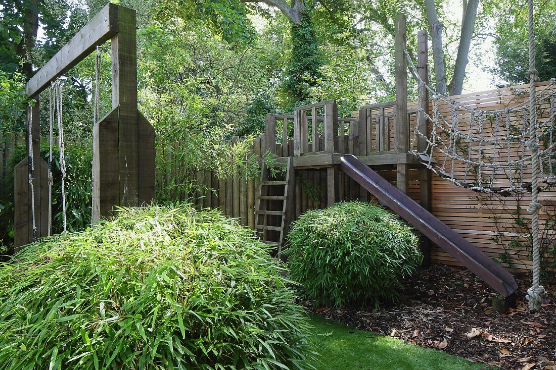 Play area with wooden climbing frame in summery garden