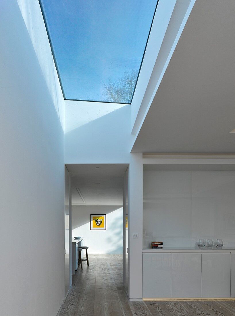 White kitchen counter and hallways with large skylight showing blue sky