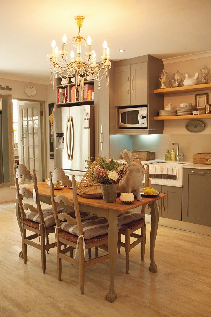 Österlich dekorierter Esstisch unter elegantem Kronleuchter in Einbauküche