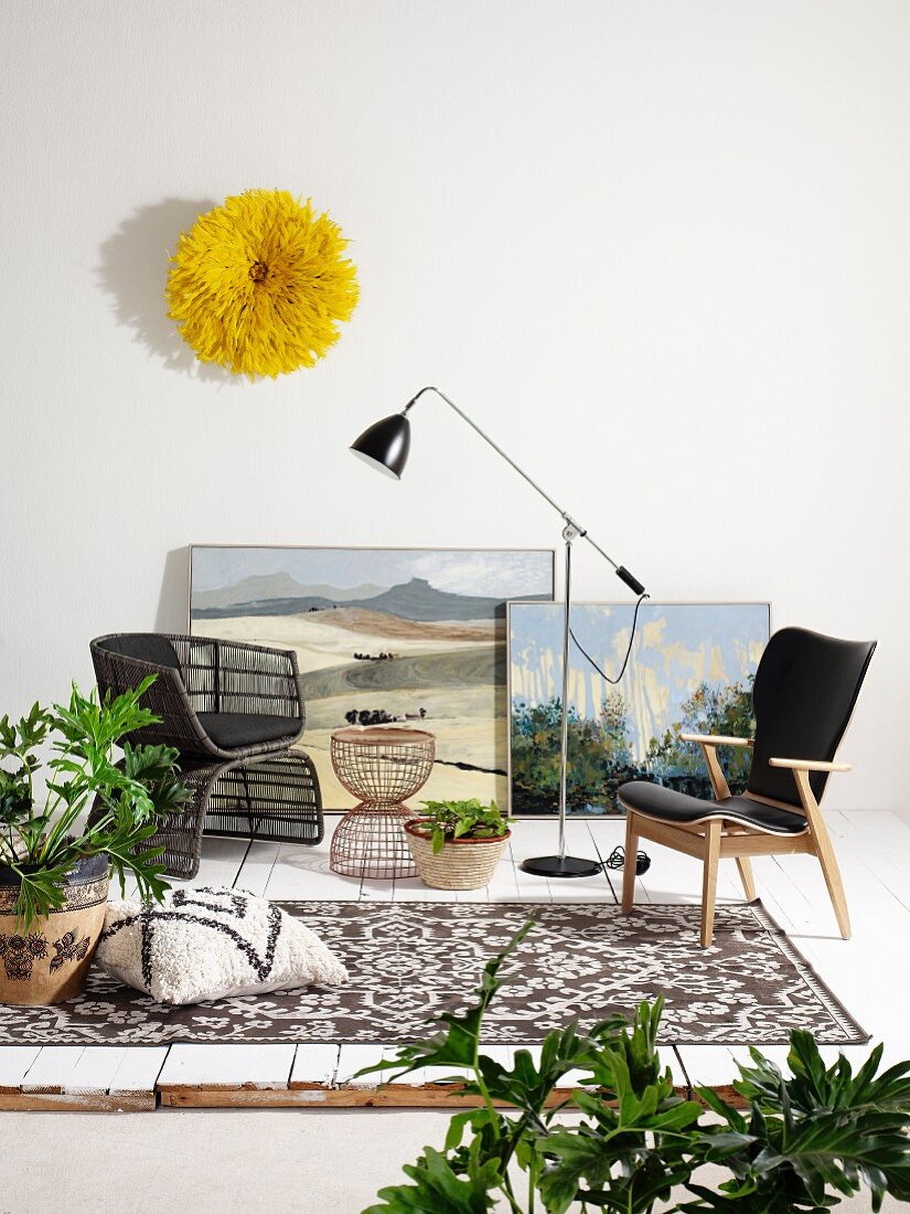 Verschiedene Sessel, Retro Stehleuchte, Zimmerpflanzen, an Wand gelber Wandschmuck