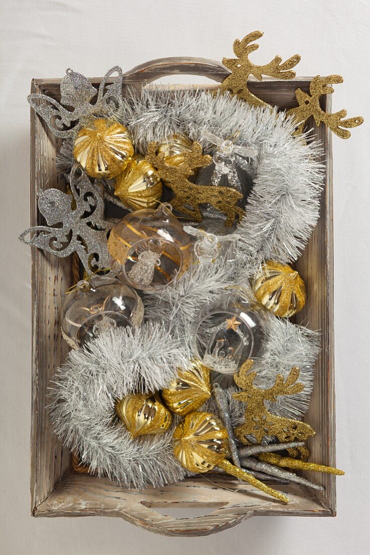 Silver and gold Christmas decorations on wooden tray