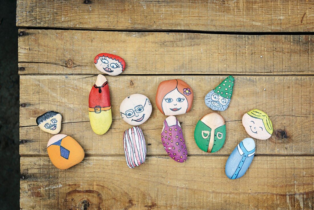 Pebbles painted as whimsical characters on rustic wooden surface
