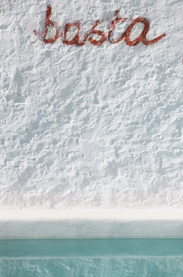Detail einer weißen Wand mit Schritzug basta