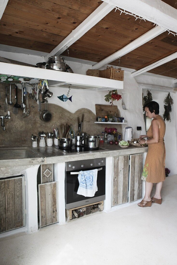 Frau in gemauerter Küche mit rustikalen Holzfronten