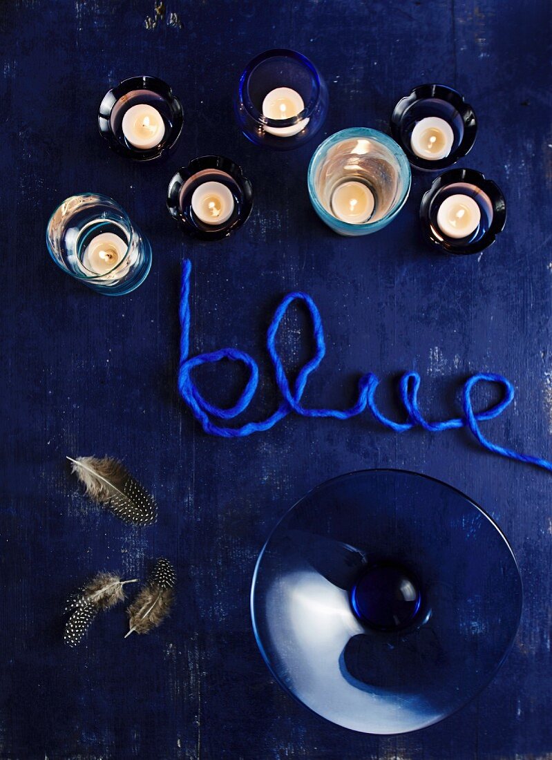 Teelichter, Glasschale und Schriftzug 'blue' auf blauem Untergrund