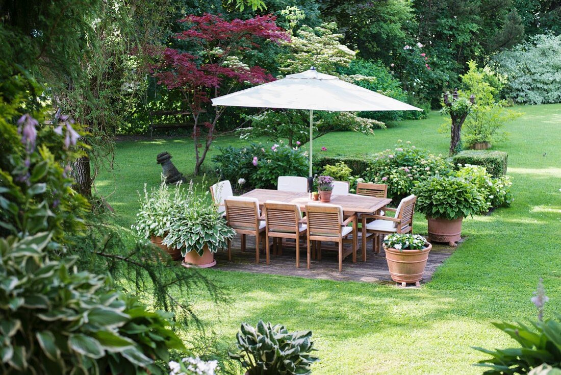 Sitzplatz mit Sonnenschirm in gepflegtem Garten