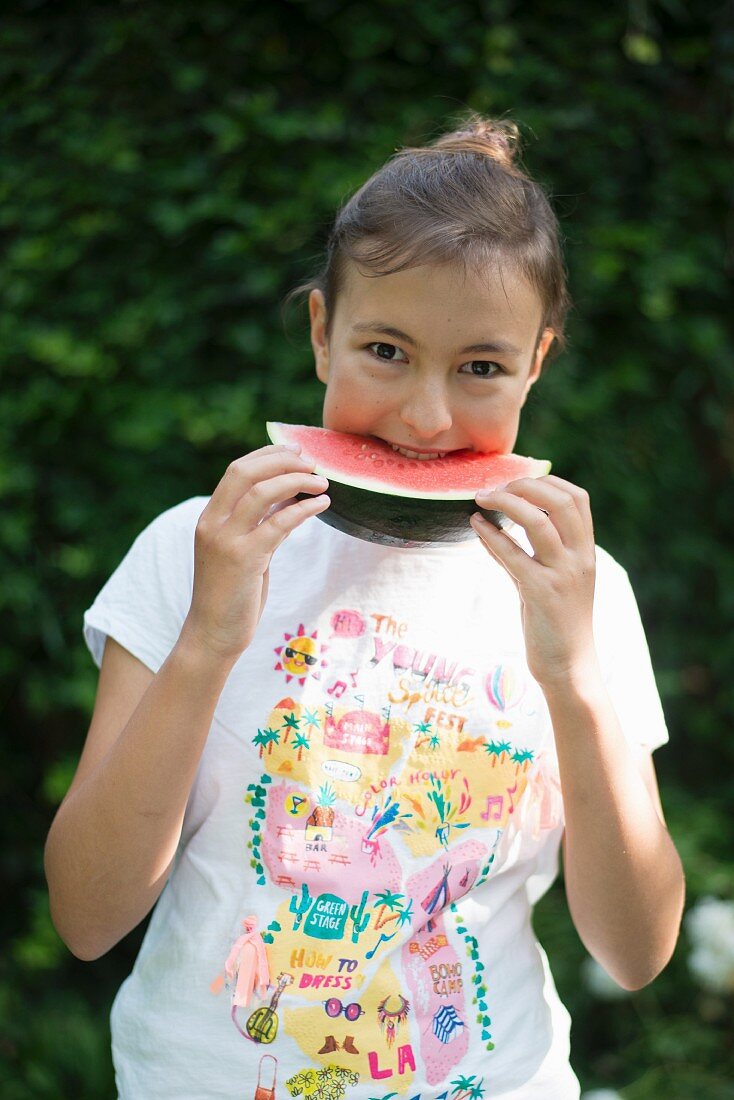 Mädchen isst Wassermelone im Garten