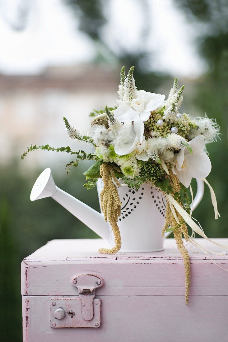 Weiß-grünes Blumenbouquet in Giesskanne mit weissen Schmetterlingsorchideen, Wiesenehrenpreis, Gartenfuchsschwanz, Fetthenne, Chrysanthemen und Samenständen von Clematis