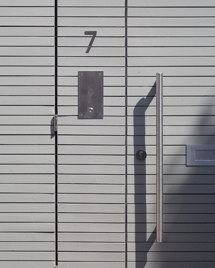 Moderne Eingangstür aus grauen Holzpaneelen mit Metallgriff (Ausschnitt)