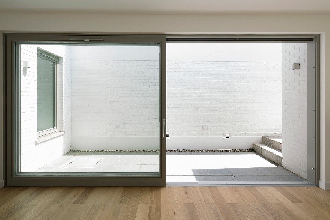 View into simple, white courtyard terrace through open sliding terrace doors