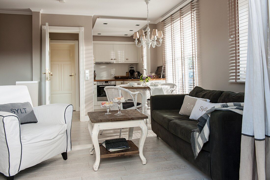 Loungebereich mit gemütlichen Polstermöbeln vor offener Einbauküche im eleganten Landhausstil