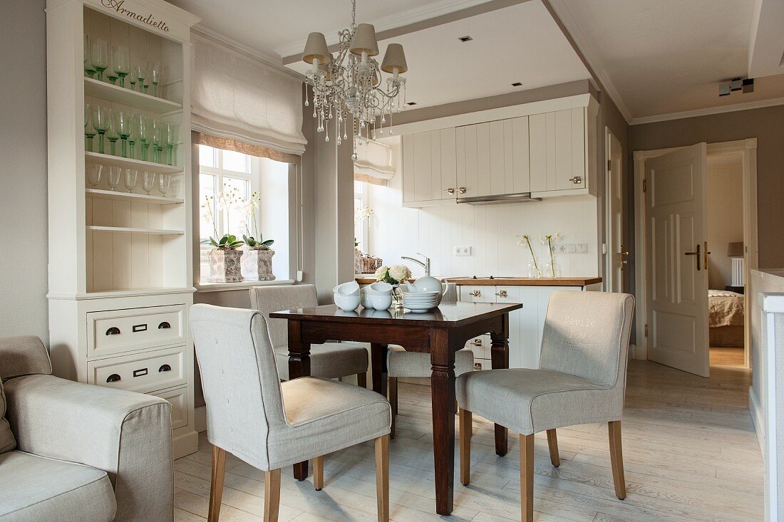 Pale upholstered dining chairs and dark brown wooden table in open-plan kitchen