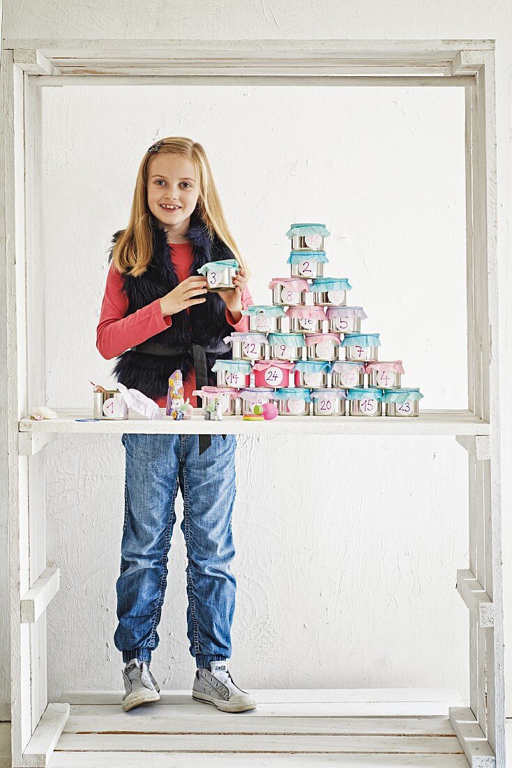 Mädchen mit DIY-Adventskalender aus dekorierten Blechdosen