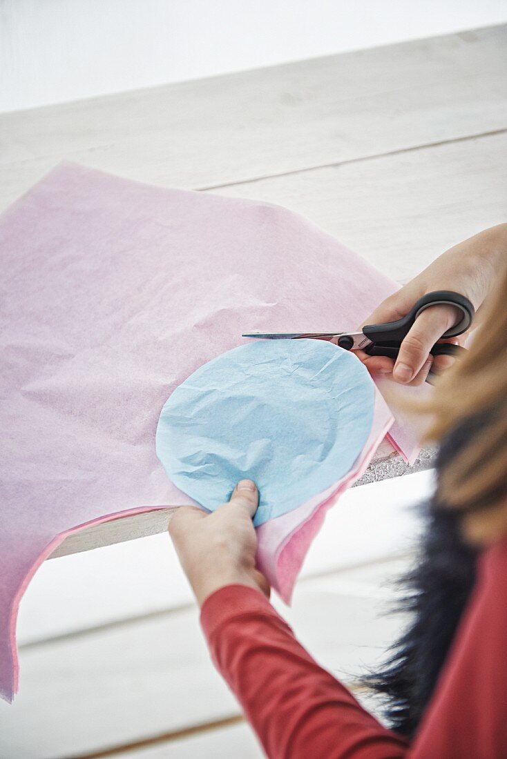Girl cutting circles out of pastel tissue paper using template