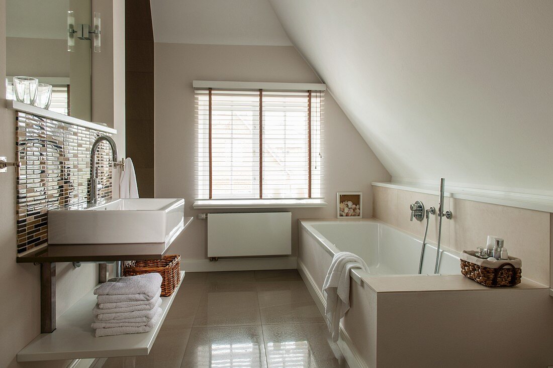 Modern bathroom in converted attic with washstand opposite fitted bathtub