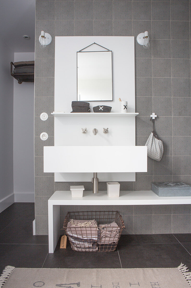 Washstand with white shelf against grey-tiled wall