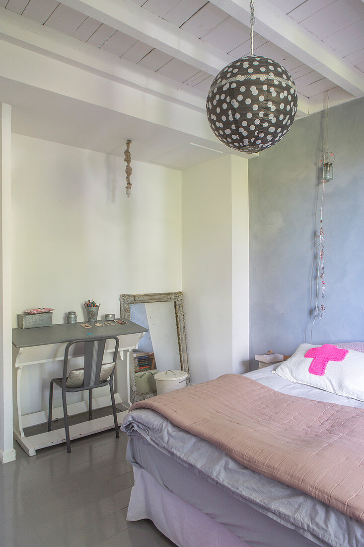 Blick über Bett mit Tagesdecke auf nostaglisches Schülerpult in renoviertem Schlafzimmer