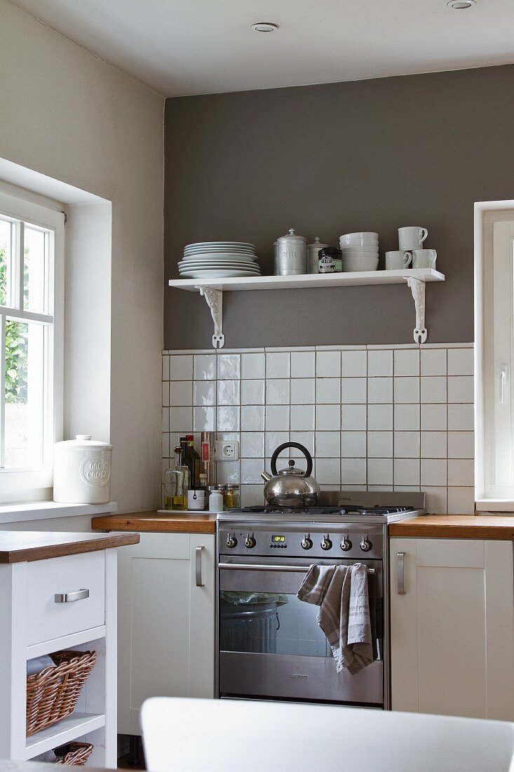 Wohnliche, helle Küche mit grauer Fläche über weissen Wandfliesen