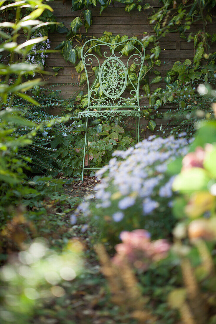 Ein verschnörkelter Metallstuhl im herbstlichen Garten