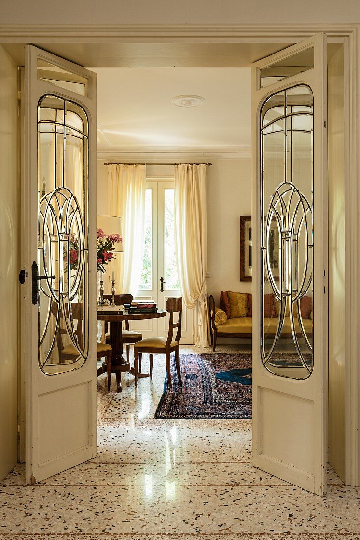 Offene Jugendstil Flügeltür mit Glasfüllung und Blick in eleganten Wohnraum mit Edelholzmöbeln