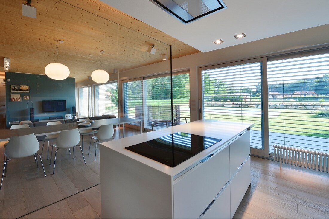 Designer kitchen island next to glass partition with view of dining area and louvre blinds on glass wall